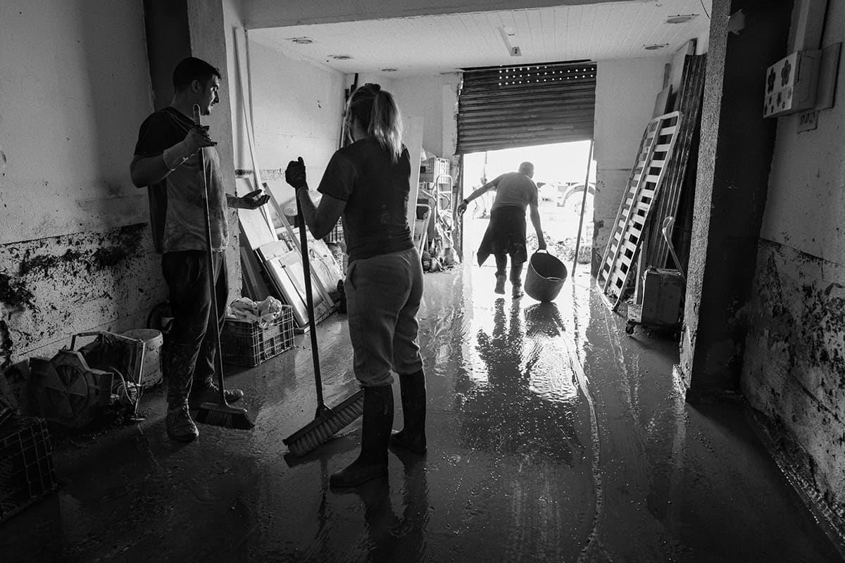 Couple cleaning mud from the interior of a small business in Torrent after the Valencia DANA flood