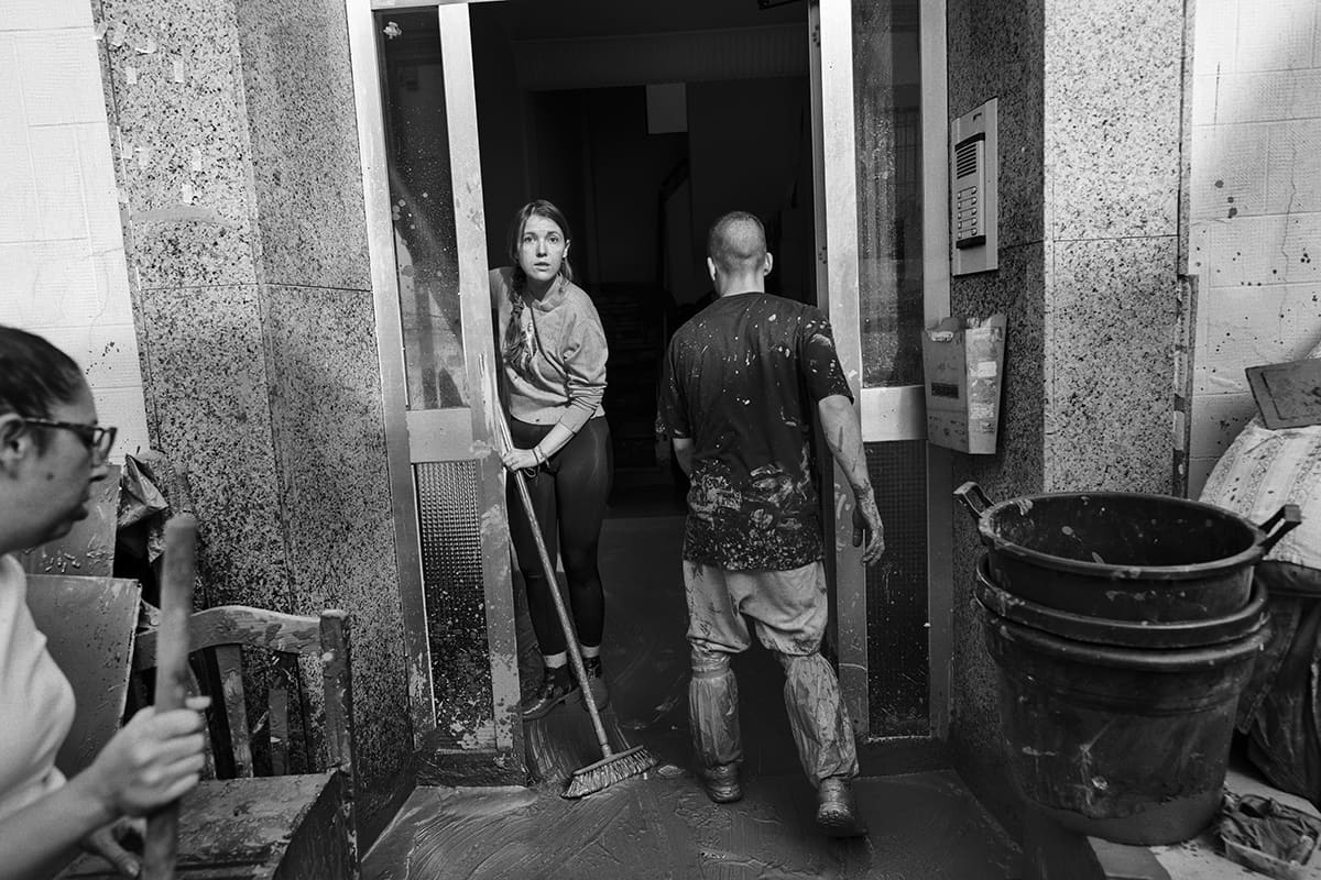 Woman sweeping mud from the entrance of her home in Paiporta after the DANA flooding in Valencia