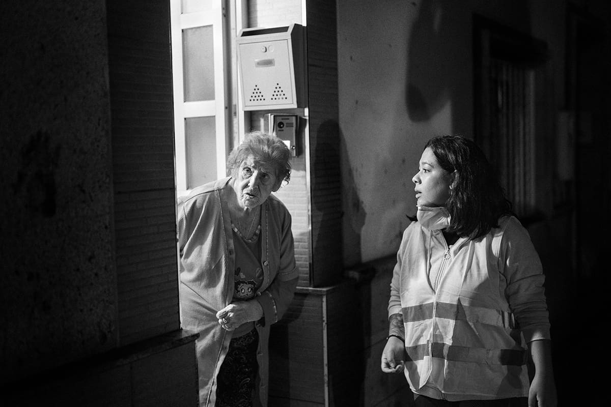 Amparo Peris cautiously opens her door to volunteer Yessica Cuellar at night in Paiporta after the Valencia DANA