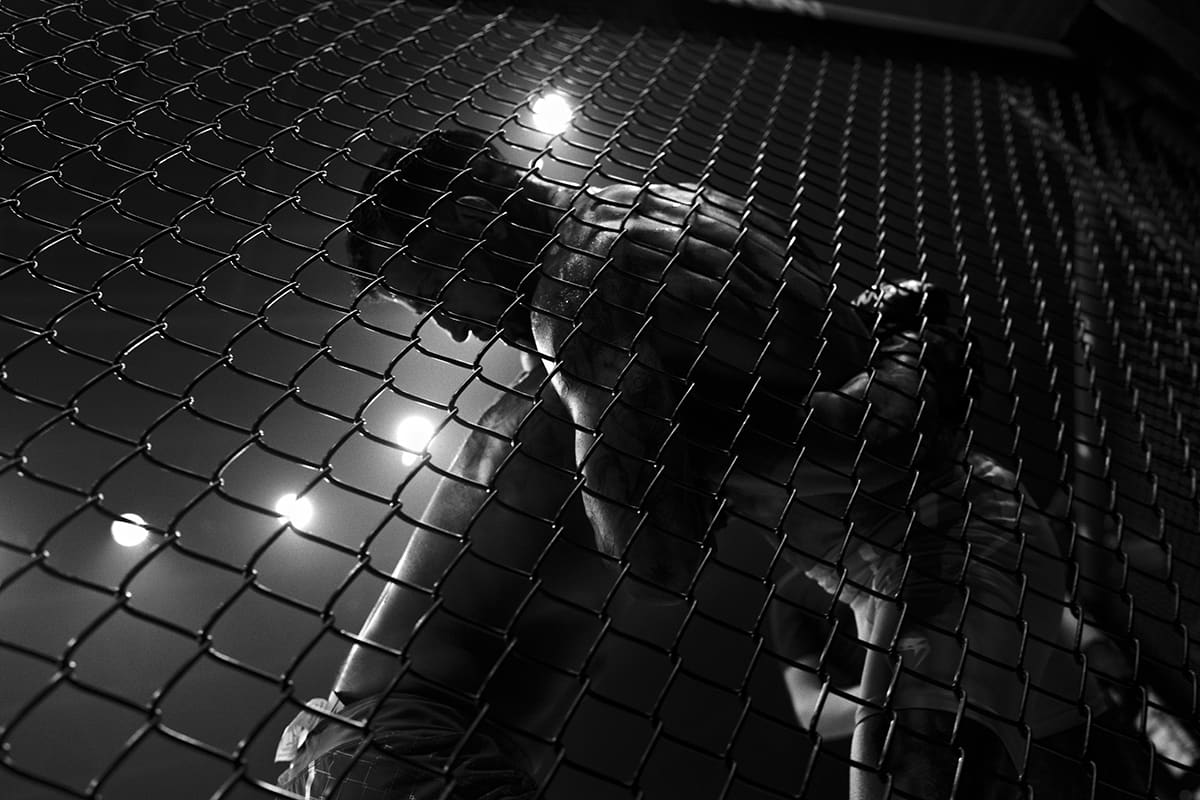 Francisco Silumsadisa grapples against the cage wall with Fernando Martin in a featherweight MMA fight in Bilbao.