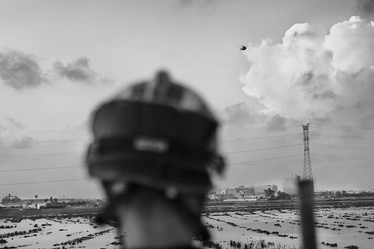UME soldier silhouetted with helicopter searching the flooded Albufera Natural Park after the 2024 Valencia DANA