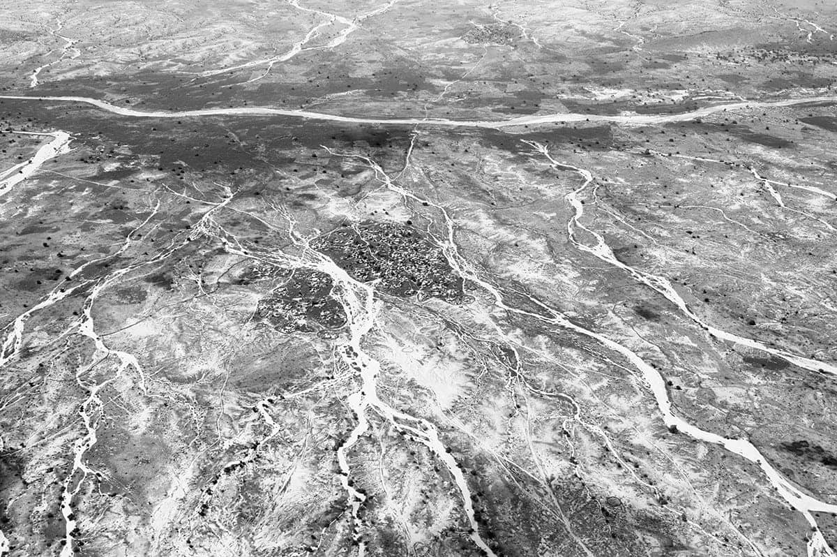 Aerial view of a Darfur village surrounded by dry riverbeds in the arid landscape of western Sudan.
