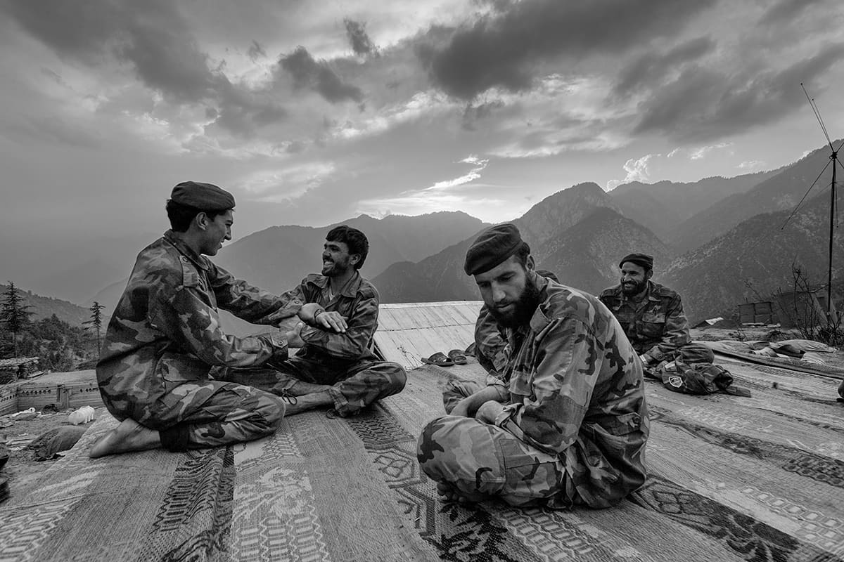 Afghan National Army soldiers laughing on the rooftop of Gowardesh Outpost at dusk, Nuristan, May 2007
