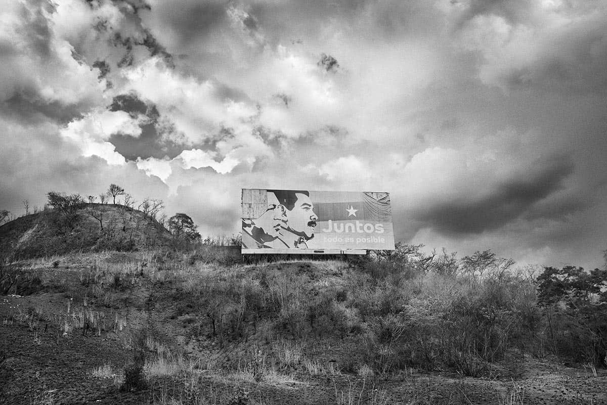 A weathered sign with the faces of Hugo Chávez and Nicolás Maduro beside the Barquisimeto–Caracas highway