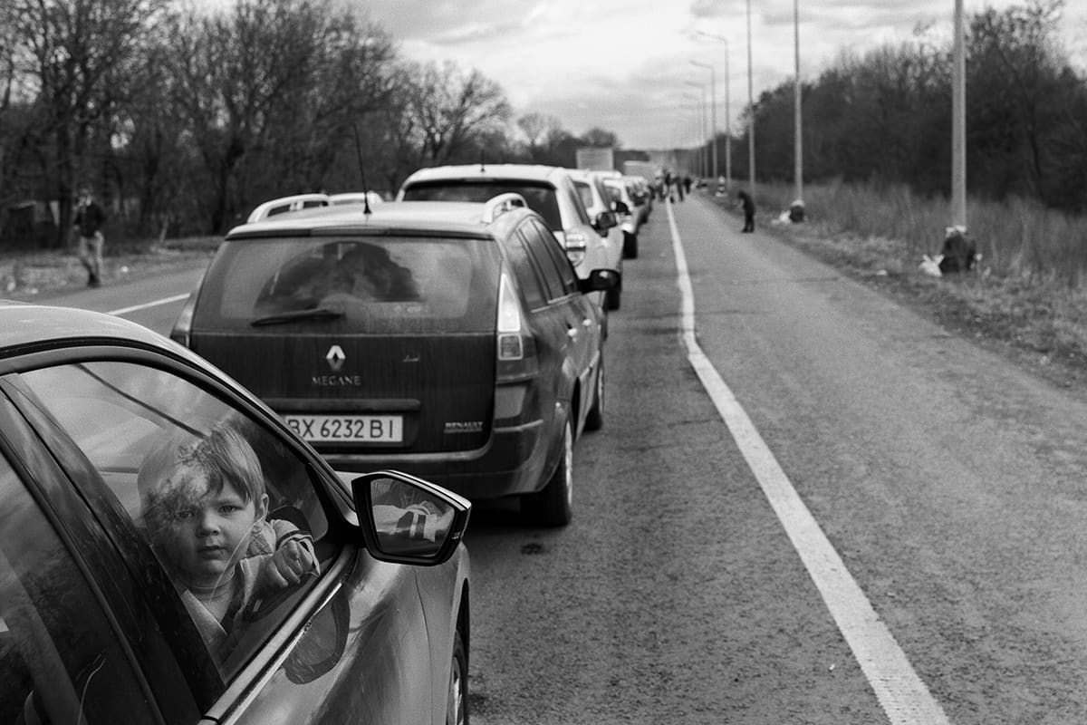 A child fleeing the war waits with his family in a car at the border crossing into Romania.