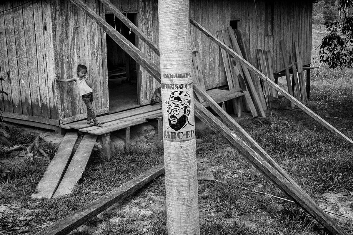 Boy stands beside a mural of FARC commander Alfonso Cano in El Guamo, Tolima, months after his death, 2016