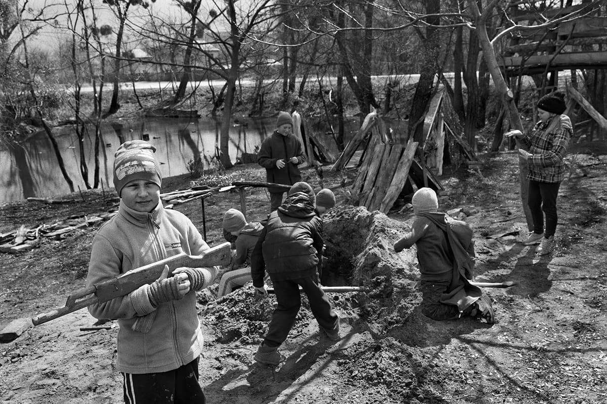 Children displaced by the war play soldiers and prisoners in the courtyard of a regional school.
