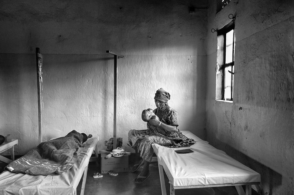 A woman holding a child on a hospital bed in the cholera ward of the Goma hospital.
