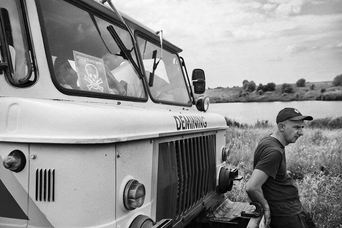 Artem, one of the two medics of a Ukrainian emergency service demining unit, rests against its armoured truck.