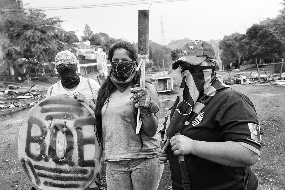 Female students pose while classmates build barricades against colectivos and the National Guard