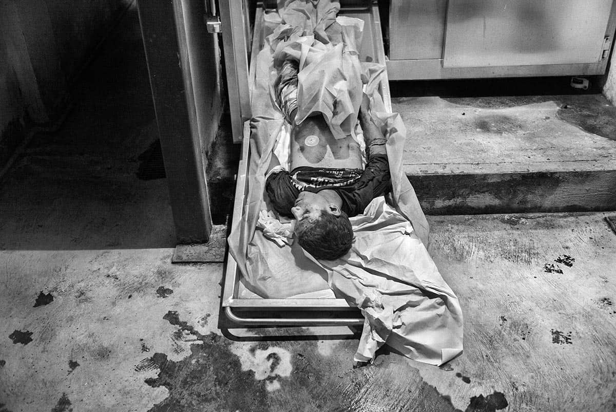 The body of a young gang member lies in the morgue of a CDI in La Dolorita, Petare