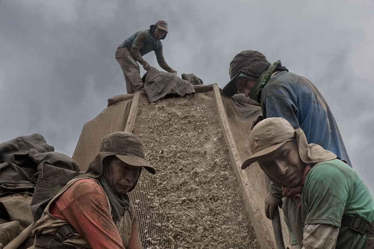 Guano workers operating a sifting chute during the harvest on Isla Asia, Peru.