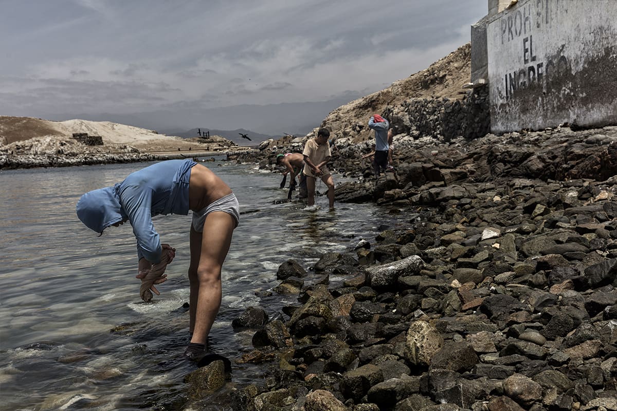Guano worker washing his clothes on the shore after his working day on Isla Asia, Peru.