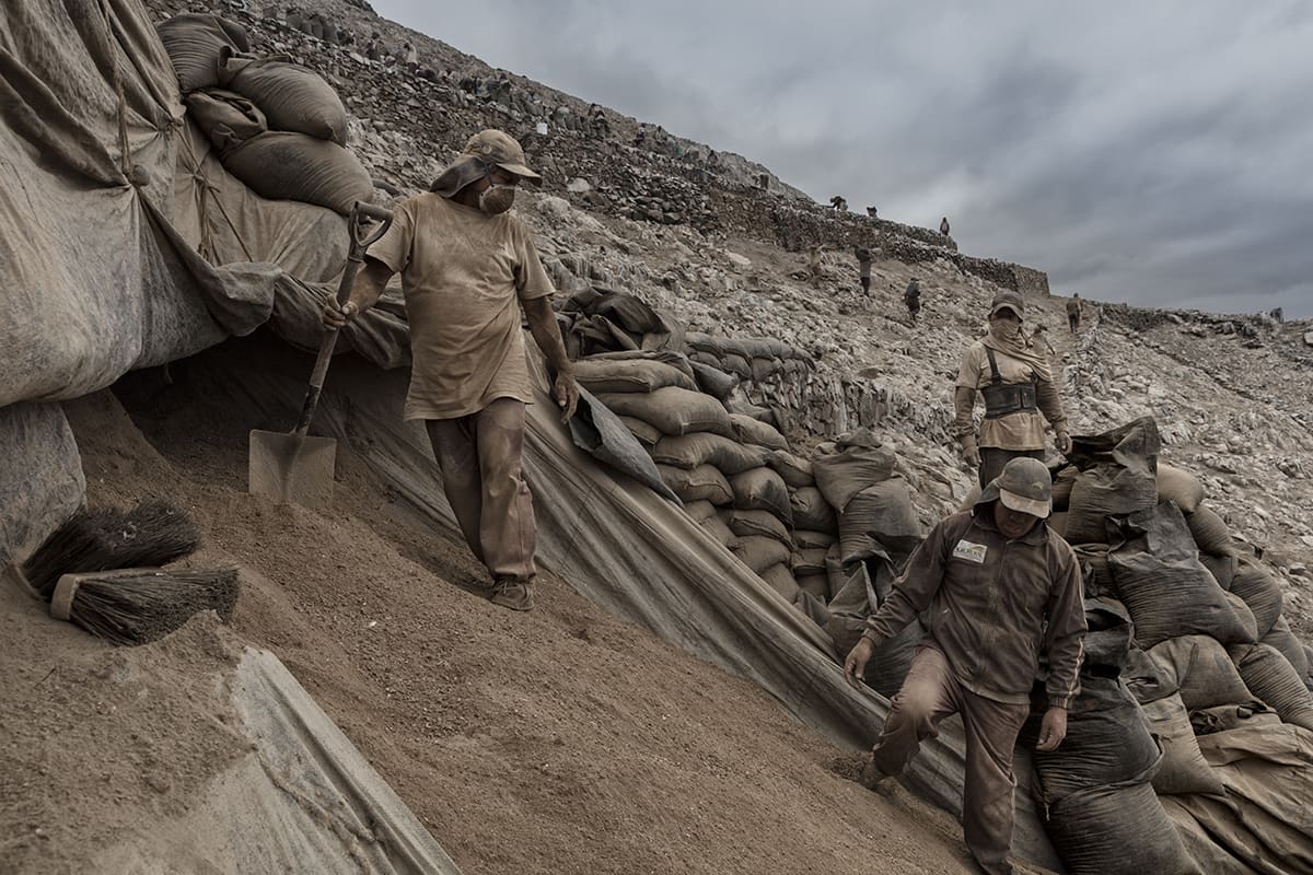 Workers with shovels sifting guano on a hillside during the extraction season on Isla Asia, Peru.