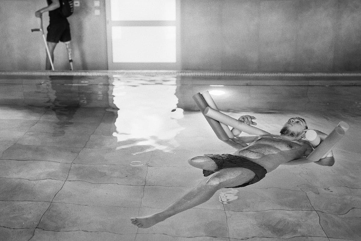 Yevhen recovers from the amputation of his right leg with his therapist in the pool of the Superheroes hospital.