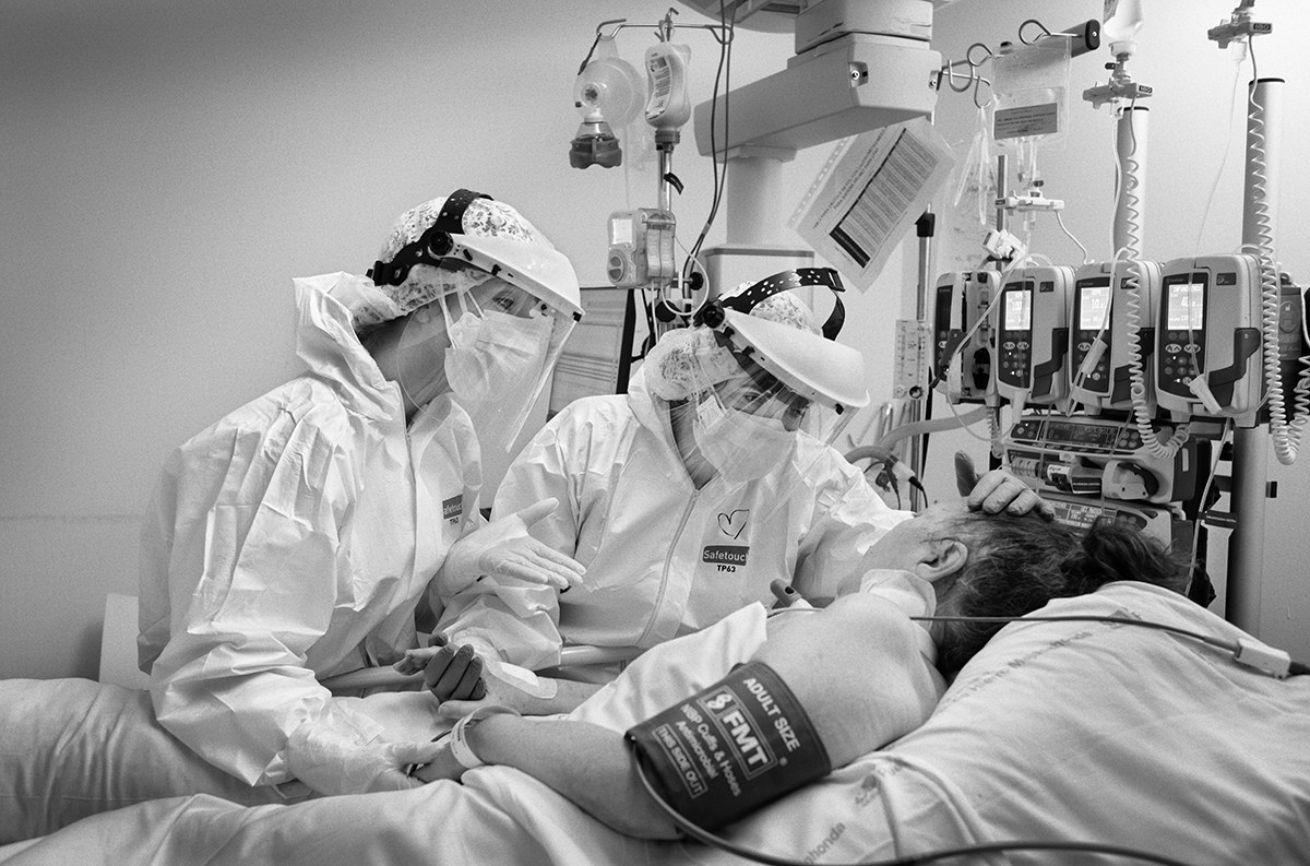 Healthcare workers in full personal protective equipment treating a COVID-19 patient in an intensive care unit in Spain.