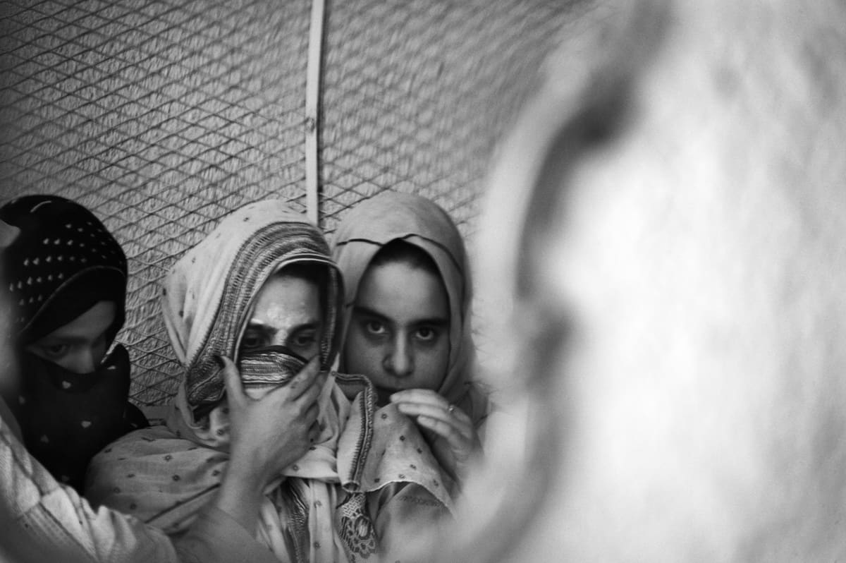Reflection in a mirror of Iraqi women showing fear as US Marines prepare to search their home in Fallujah