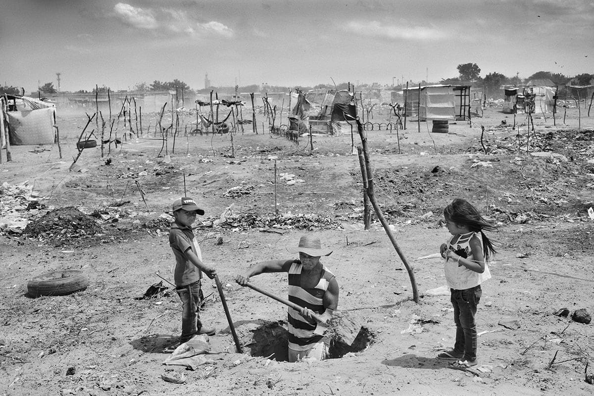 José Luis Rincón and his children build a septic tank in the migrant settlement 'La Pista'