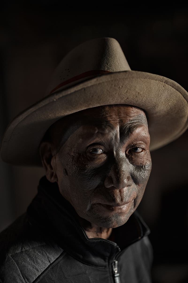 Konyak former headhunter wearing a felt hat, his face covered by dark traditional tattoos.