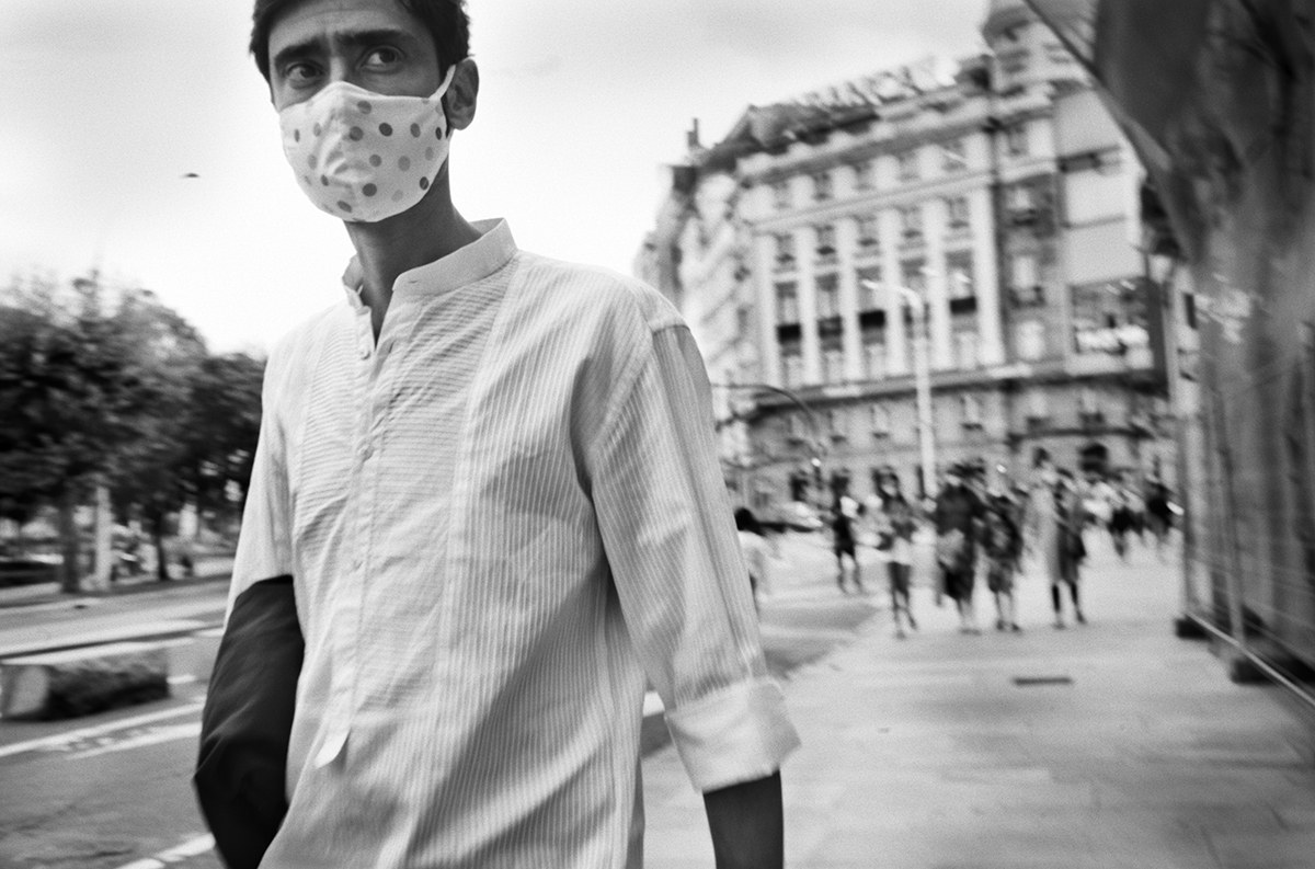 Man wearing a homemade fabric face mask walking along a city street in Spain during the new normal.