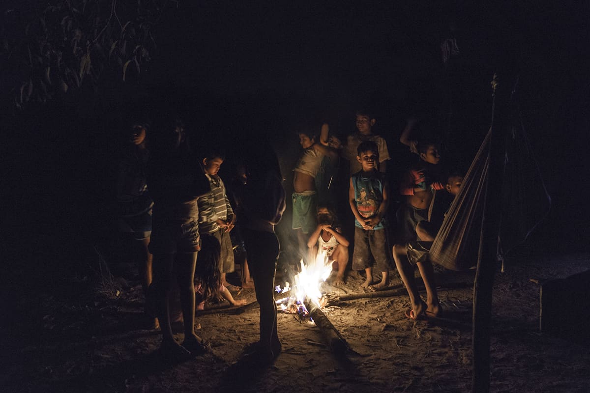 Children of a Manoki Indigenous community gathered around a fire at night