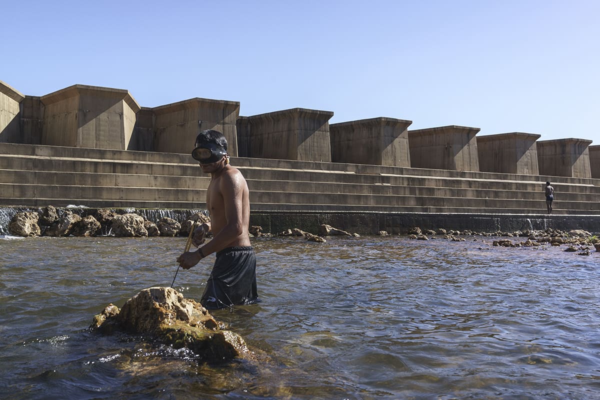 Manoki Indigenous man fishing near a dam at the edge of his territory