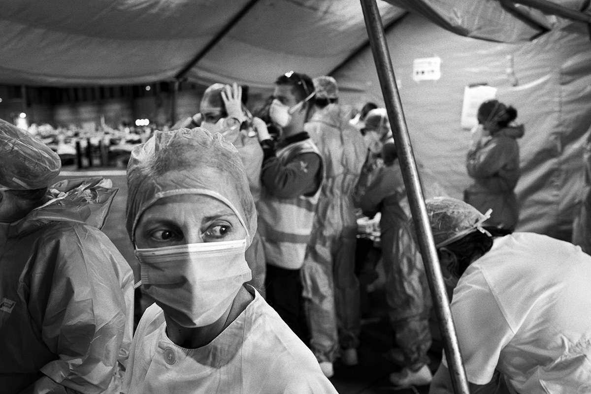 Nurse wearing a face mask and surgical cap inside a crowded Spanish hospital during the COVID-19 pandemic.