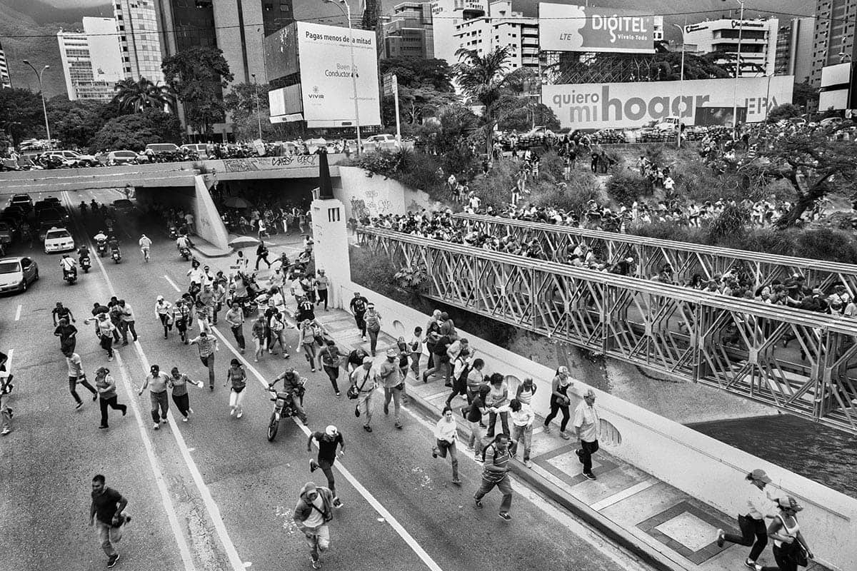 Opposition demonstrators flee from the Bolivarian National Guard during a protest in Caracas