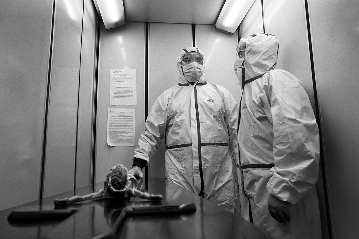 Two paramedics in protective equipment standing with a stretcher inside an elevator during the COVID-19 pandemic in Spain.