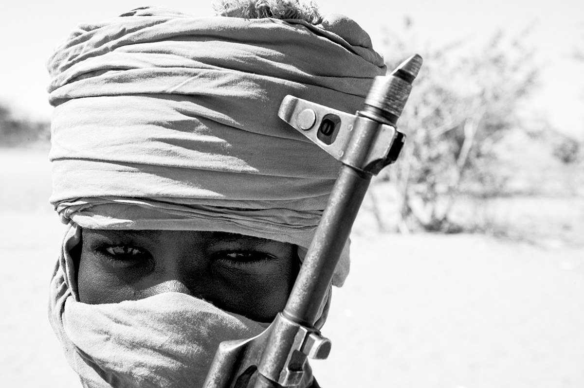 Darfur rebel fighter with his face covered by a turban behind the barrel of an AK-47 rifle in western Sudan.