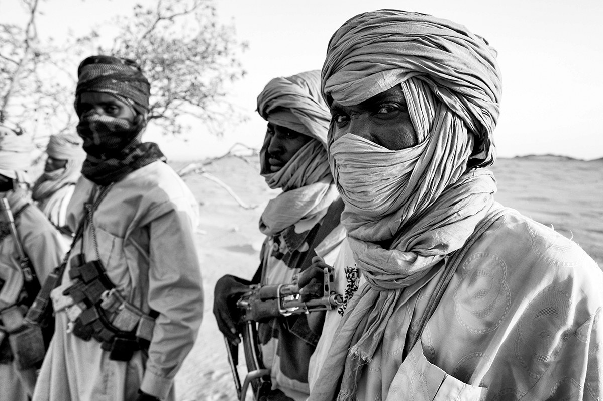 Group of Darfur rebel fighters with faces wrapped in turbans standing in the desert of Sudan.