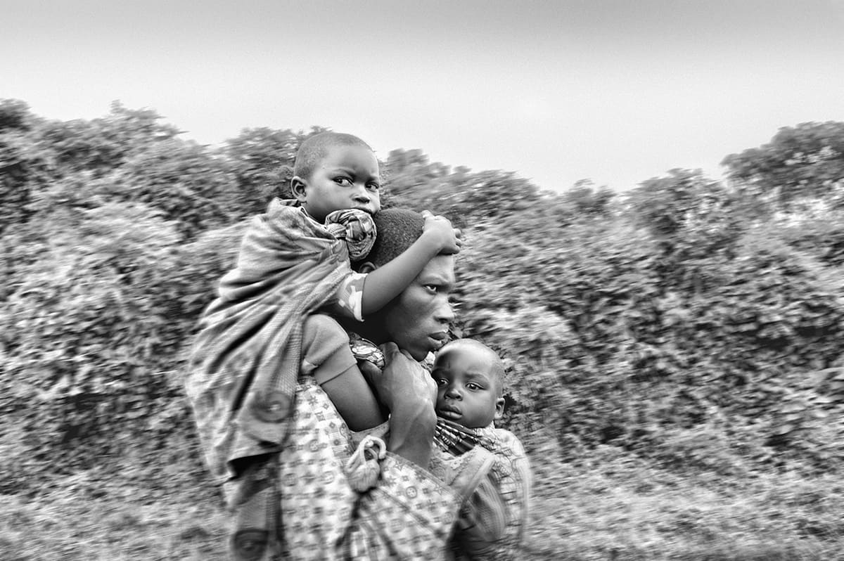 A woman carrying two children on her back as she flees the fighting in North Kivu, eastern Congo.