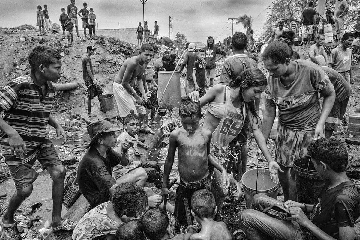 Residents collect water from improvised sources in Maracaibo amid the collapse of public services