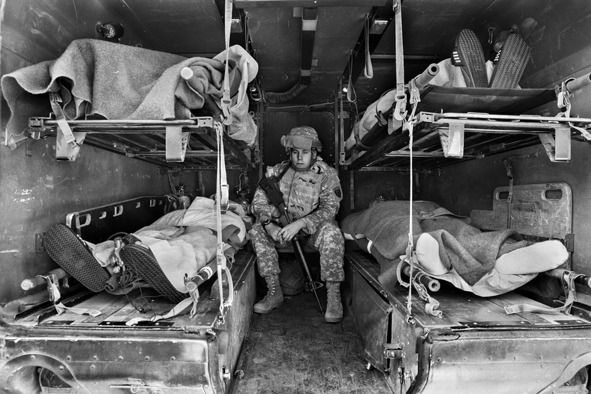Seigtz, a soldier from the 28th Combat Support Hospital, sits alone inside the military ambulance used to transport the dead — an image of the human cost of conflict in the Iraq War 2003