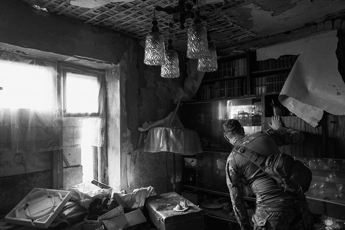 A Ukrainian soldier searches an abandoned house for information in Dementiivka.