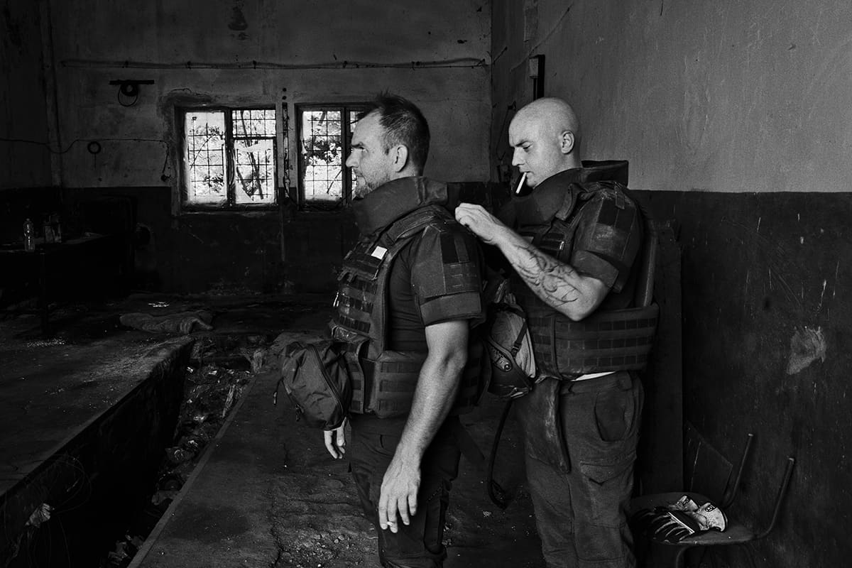 Ylia puts on his protective vest before working on an abandoned Russian military position in eastern Ukraine.