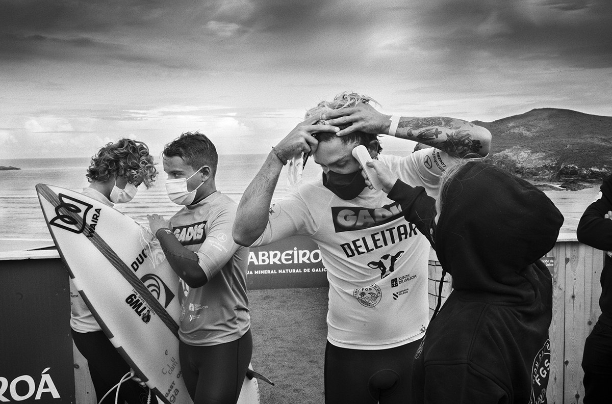 Surfers wearing face masks preparing for a competition on a beach in Galicia during the COVID-19 pandemic.