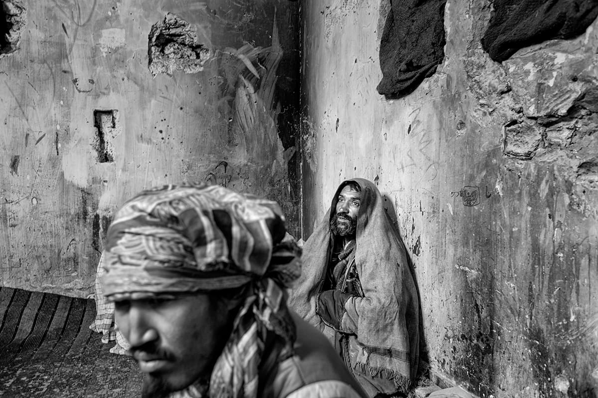 Two Afghan heroin addicts inside the ruins of the Russian Cultural Centre in Kabul, February 2009
