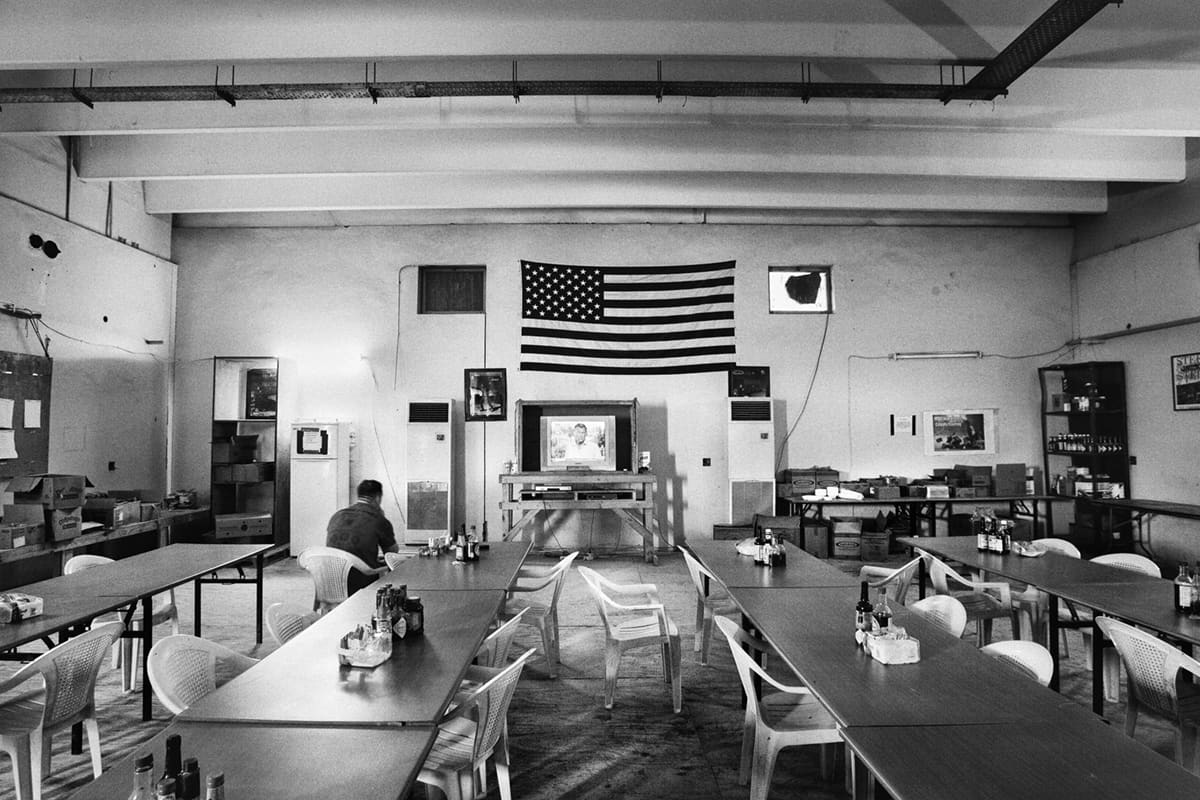 A lone US Marine from Bravo Company watches the news under a large American flag in the base cafeteria, set inside Fallujah's former train station