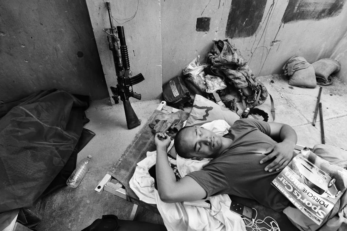 A US Marine from Bravo Company sleeps on a cot next to his rifle and gear inside the Shoker base in Fallujah