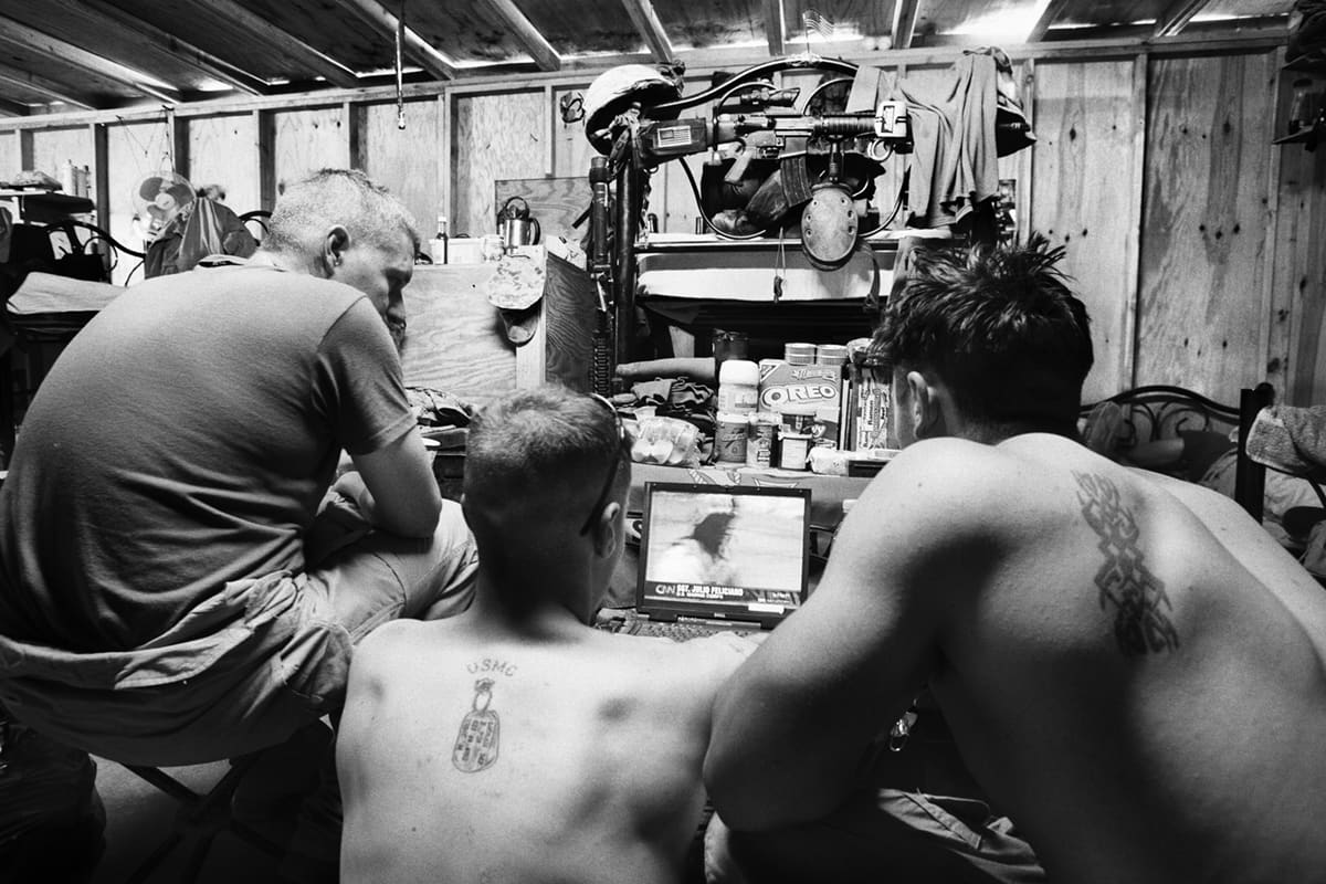 US Marines from Bravo Company gathered around a laptop watching CNN news about Iraq inside their barracks in Fallujah
