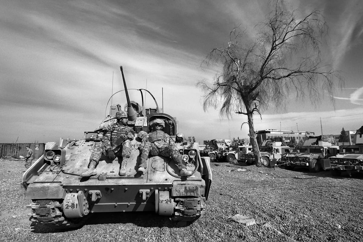 US Quick Reaction Force soldiers resting in the sun on top of a Bradley fighting vehicle while waiting to be activated in Baghdad