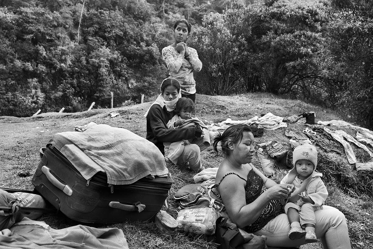 A Venezuelan migrant family walks along the highway toward Bogotá carrying their children