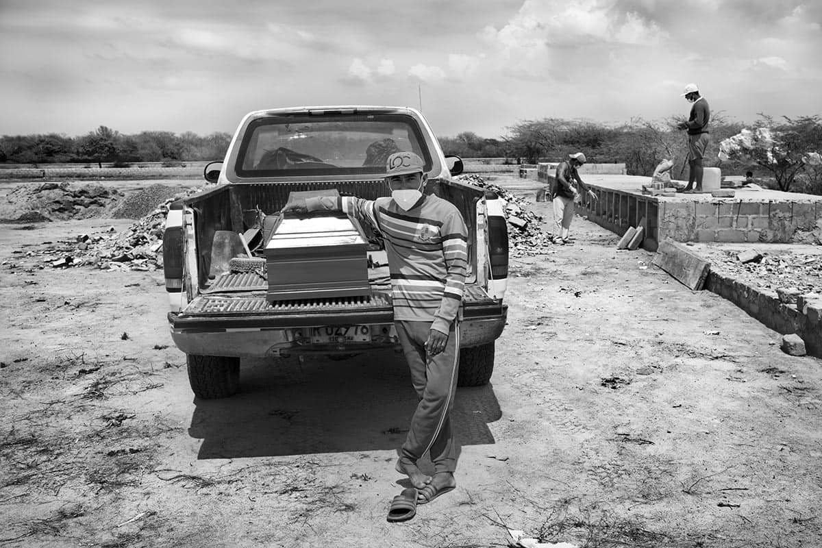 Willy José Sánchez waits beside the body of an unidentified Venezuelan woman before burial