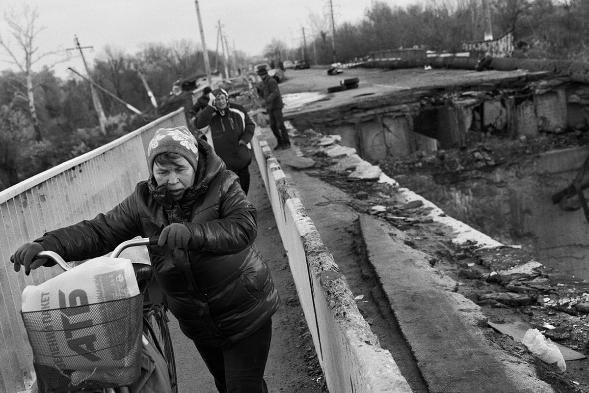 A woman crosses the bridge destroyed by fighting between Ukrainian and Russian troops in Kupiansk.