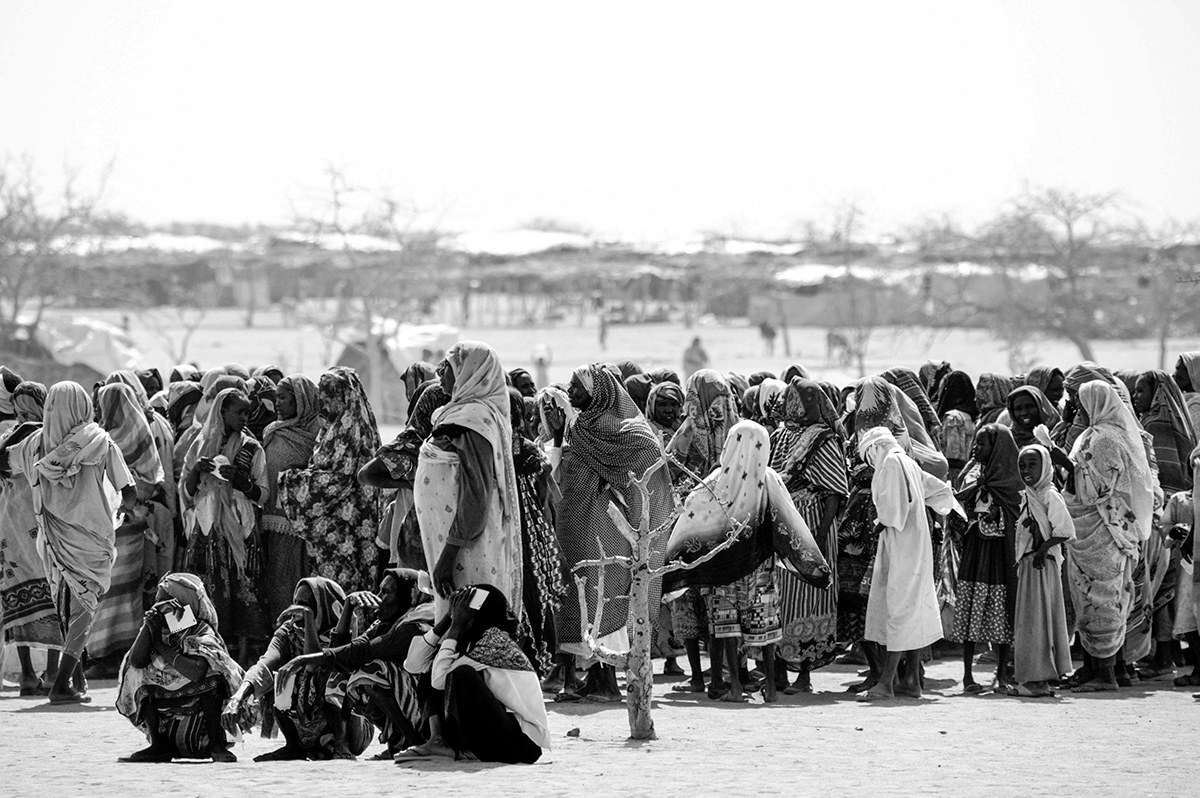 Crowd of displaced women waiting in line for a food distribution at a refugee camp in Darfur.